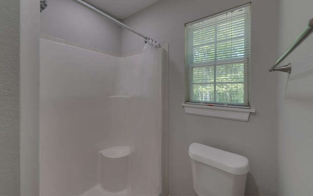 full bathroom featuring toilet and a shower with shower curtain