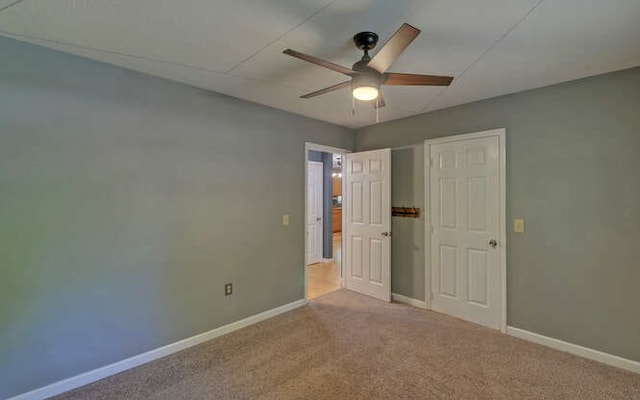unfurnished bedroom with carpet floors, a ceiling fan, and baseboards