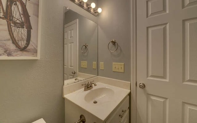 half bath featuring a textured wall and vanity