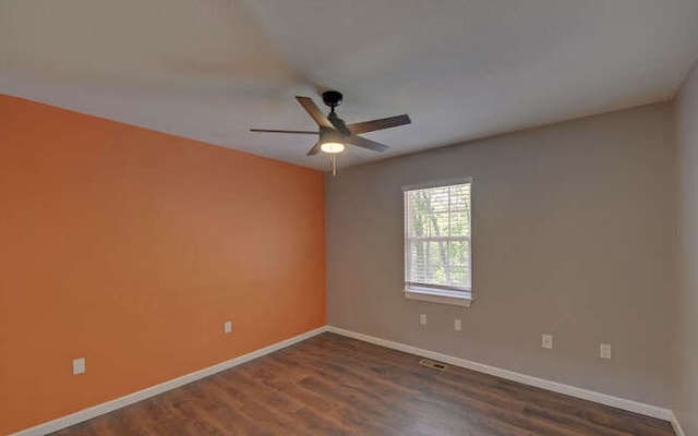 empty room featuring baseboards, ceiling fan, dark wood finished floors, and visible vents