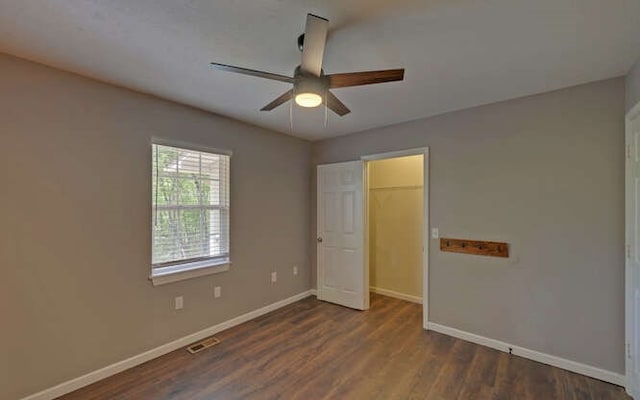 unfurnished bedroom featuring a ceiling fan, baseboards, visible vents, and dark wood-style floors
