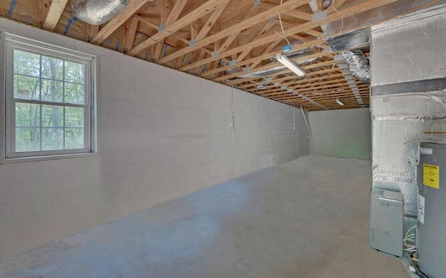 basement featuring concrete block wall and electric water heater