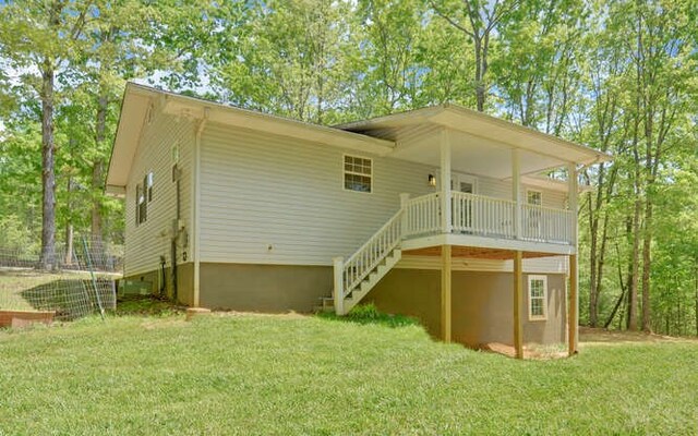 rear view of property with a lawn, stairway, and a deck