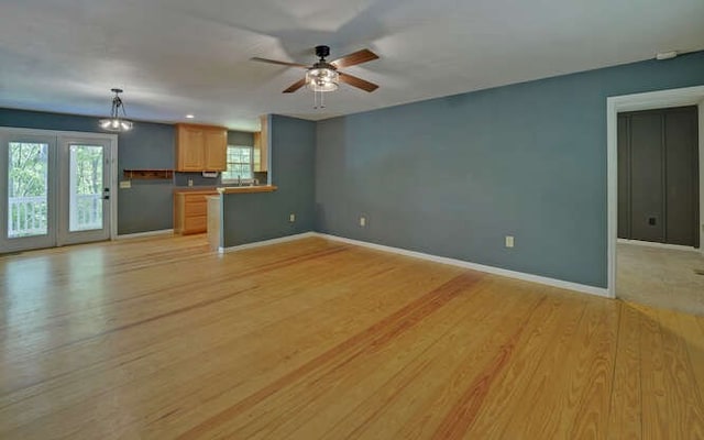 unfurnished living room with baseboards, a ceiling fan, and light wood finished floors