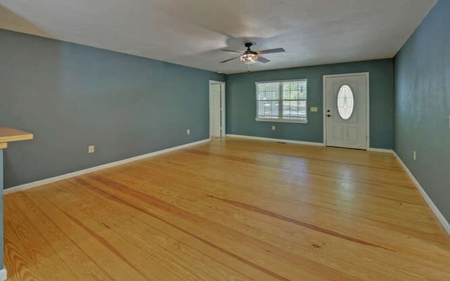 foyer entrance with baseboards, a ceiling fan, and light wood-style flooring
