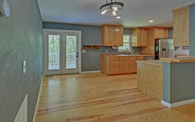 kitchen featuring light countertops, a sink, stainless steel fridge, light brown cabinets, and light wood-style flooring