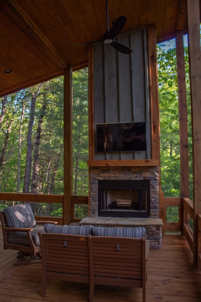 wooden deck with a stone fireplace and ceiling fan