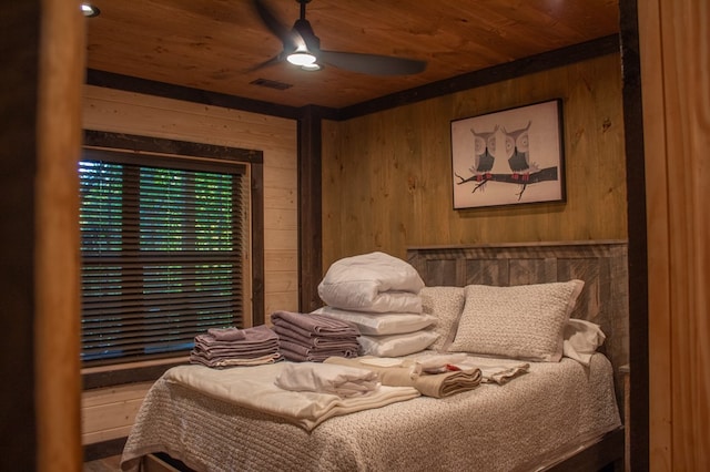 bedroom with ceiling fan, wooden walls, and wood ceiling