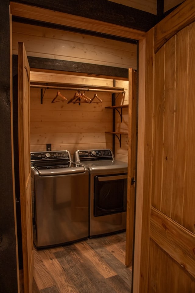 laundry room with wood walls, dark wood-type flooring, and washing machine and clothes dryer