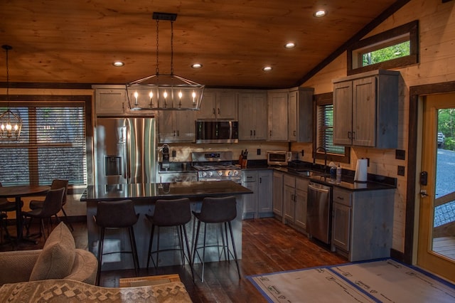 kitchen with pendant lighting, lofted ceiling, sink, appliances with stainless steel finishes, and a kitchen island