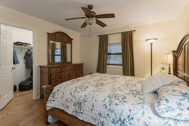 bedroom with ceiling fan, wood-type flooring, ornamental molding, and a spacious closet