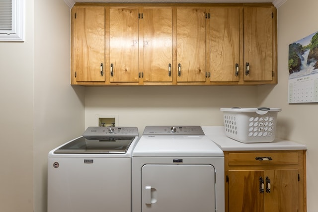 laundry room featuring washer and clothes dryer, cabinets, and ornamental molding