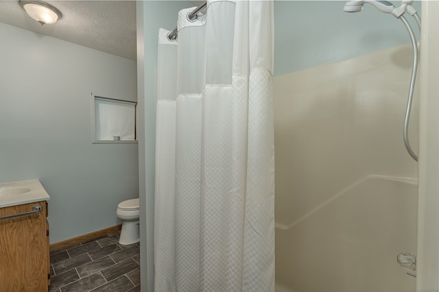 bathroom with vanity, a textured ceiling, tile patterned flooring, and toilet