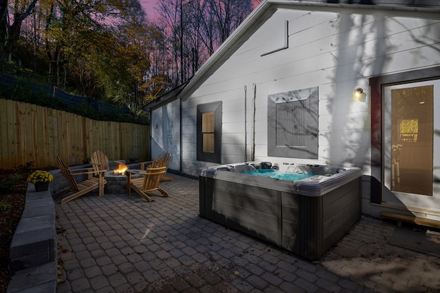 view of patio / terrace featuring a fire pit, fence, and a hot tub