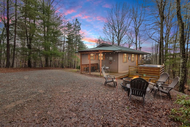 exterior space with a fire pit, driveway, and metal roof