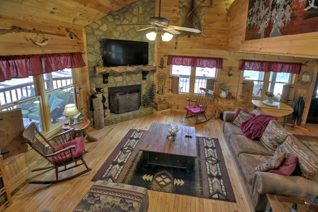 living room featuring plenty of natural light, wood-type flooring, a fireplace, and wooden walls