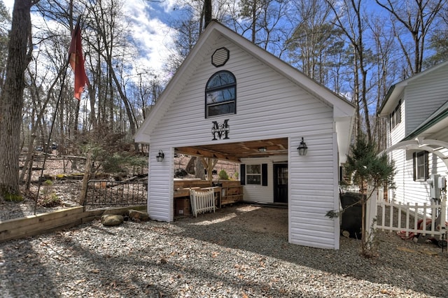 rear view of property featuring an outbuilding and fence