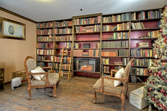 sitting room featuring wall of books and wood finished floors