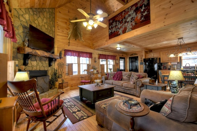 living area with wooden ceiling, light wood-style flooring, wood walls, a fireplace, and a ceiling fan