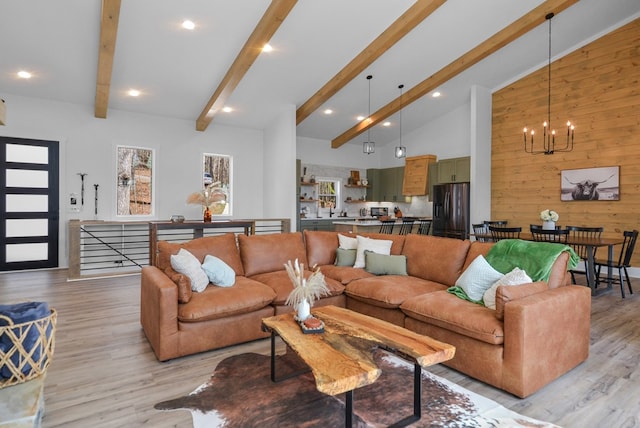 living room featuring light hardwood / wood-style flooring, lofted ceiling with beams, a notable chandelier, and wooden walls