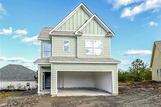 view of front facade with board and batten siding, a shingled roof, and a garage