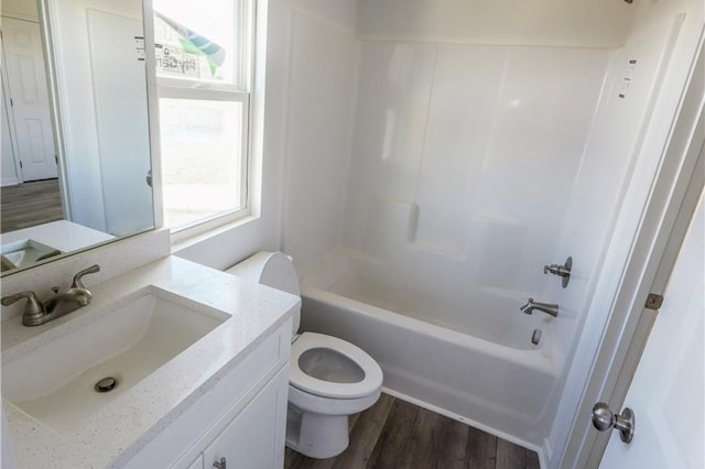 bathroom featuring healthy amount of natural light, toilet, wood finished floors, and vanity