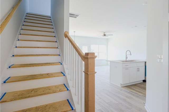 stairway featuring wood finished floors and ceiling fan