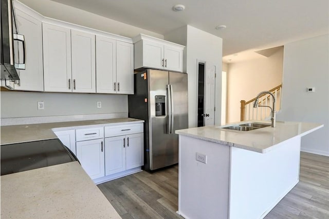 kitchen featuring stainless steel refrigerator with ice dispenser, a sink, wood finished floors, and white cabinets