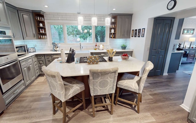 kitchen featuring hanging light fixtures, wood-type flooring, a kitchen island, and tasteful backsplash