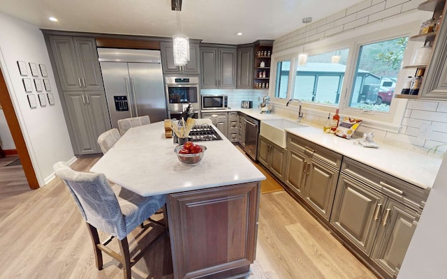 kitchen featuring appliances with stainless steel finishes, pendant lighting, sink, a breakfast bar area, and a center island