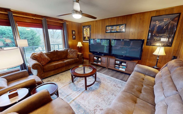 living room featuring light hardwood / wood-style floors, ceiling fan, and wood walls