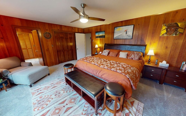 bedroom with carpet flooring, wooden walls, and ceiling fan