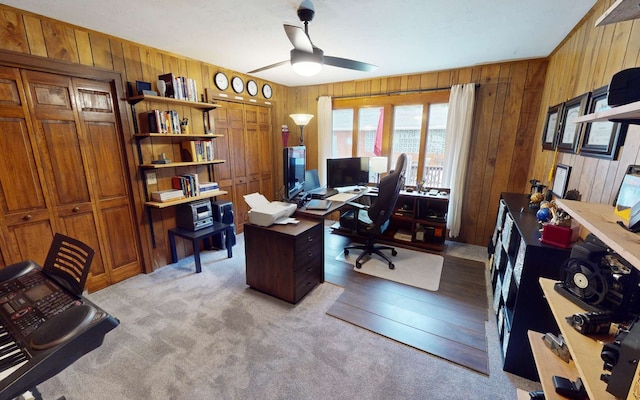 carpeted office featuring ceiling fan and wooden walls