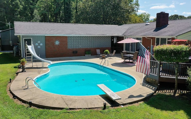 view of pool featuring a wooden deck, a yard, a water slide, and a diving board