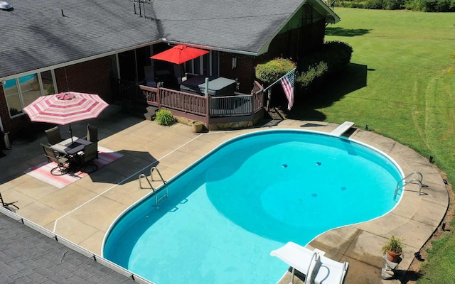 view of swimming pool with a wooden deck, a water slide, a diving board, and a lawn