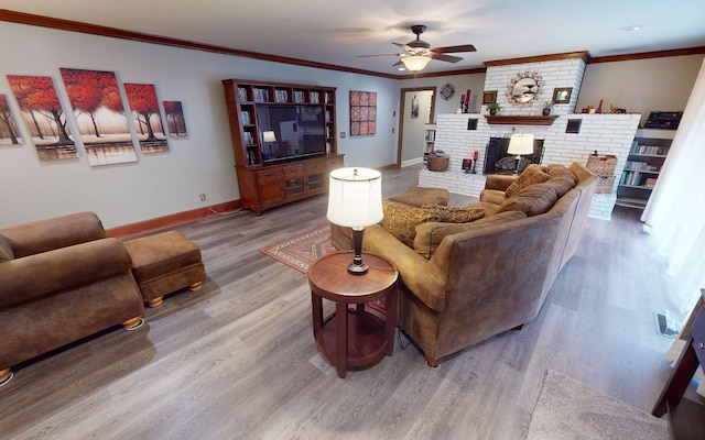 living room featuring crown molding, ceiling fan, wood-type flooring, and a brick fireplace