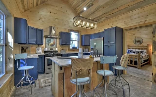 kitchen with high vaulted ceiling, blue cabinetry, stainless steel appliances, ventilation hood, and a kitchen bar