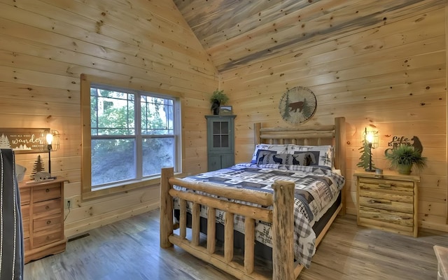 bedroom with lofted ceiling, wooden walls, and hardwood / wood-style floors