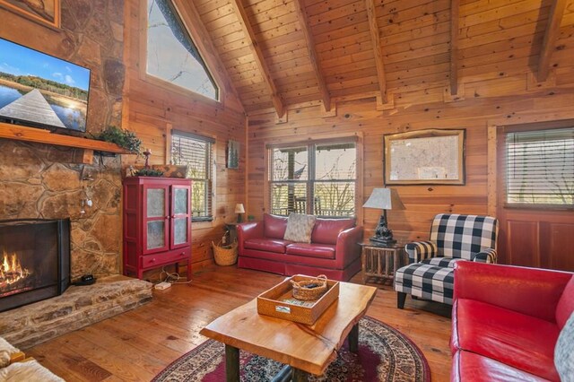 living area with wood ceiling, plenty of natural light, wood-type flooring, beam ceiling, and wood walls