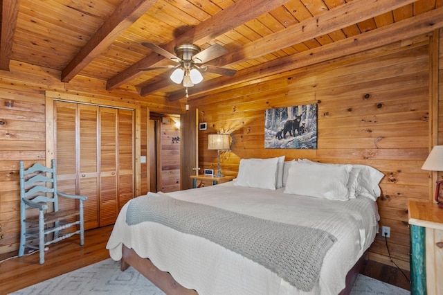 bedroom with wood finished floors, wooden walls, wood ceiling, beam ceiling, and a closet