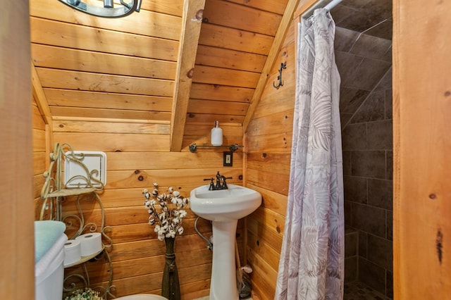 bathroom with vaulted ceiling, a stall shower, wooden ceiling, wooden walls, and a sink