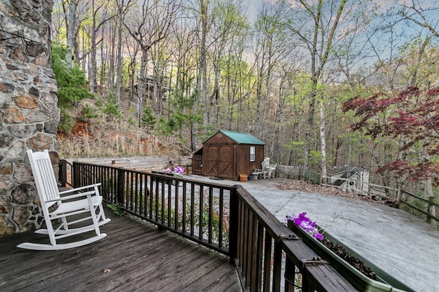 wooden deck featuring a storage shed, an outdoor structure, and fence