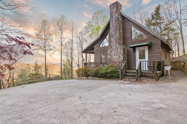 rear view of house featuring a chimney and fence