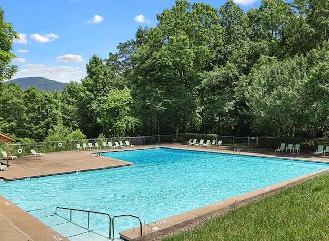 community pool featuring fence, a patio, and a mountain view