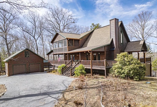 exterior space with an outbuilding, a chimney, a detached garage, and a shingled roof