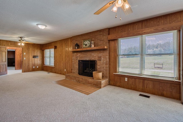 2915 Airport Rd, Marble, NC 28905 - unfurnished living room with carpet flooring, ceiling fan, wood walls, and a brick fireplace