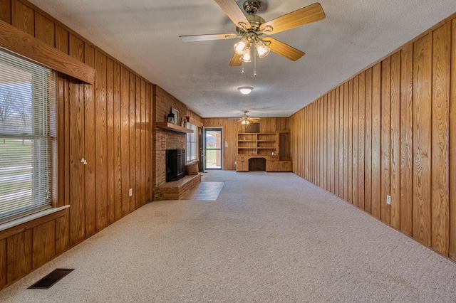 2915 Airport Rd, Marble, NC 28905 - unfurnished living room featuring visible vents, a brick fireplace, and wood walls