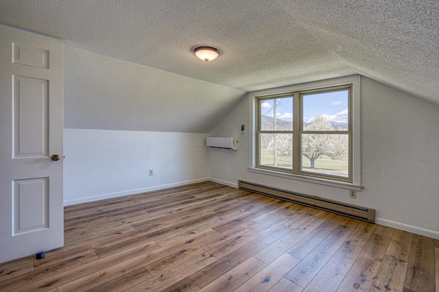 2915 Airport Rd, Marble, NC 28905 - additional living space with a textured ceiling, wood-type flooring, a baseboard radiator, baseboards, and an AC wall unit