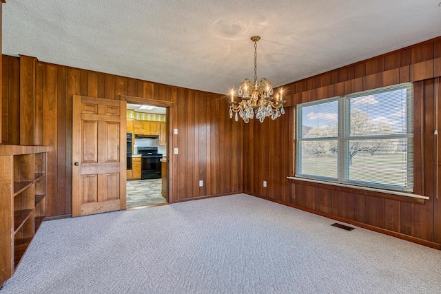 2915 Airport Rd, Marble, NC 28905 - unfurnished room with wooden walls, visible vents, an inviting chandelier, and carpet