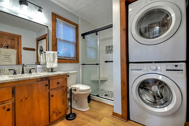 clothes washing area with light wood-type flooring, sink, and stacked washer and dryer